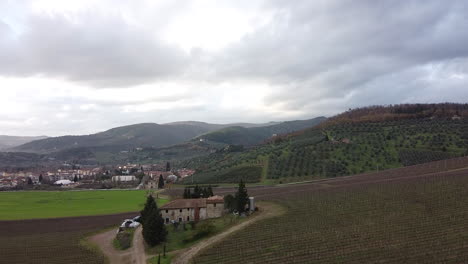 Frescobaldi-vineyard-harvest-aerial-view-towards-rural-farmhouse,-Chianti-wine-area-hillside