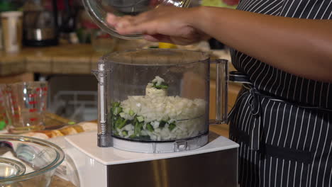 Woman-pours-chopped-jalapeno-peppers-and-onions-into-food-processor,-CLOSEUP