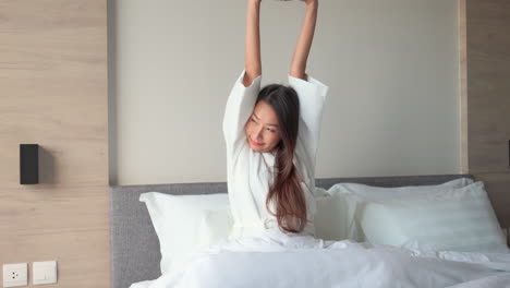 Attractive-Asian-Woman-Stretching-in-Bed-On-Beautiful-Morning-After-Good-Sleep,-Static-Shot-With-Copy-Space
