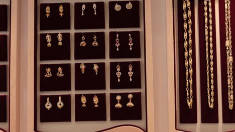 Panning-shot-of-arranged-gold-jewelry-or-jewellery-at-showroom---Concept-of-greedy,-luxury,-wealth-and-dreaming-for-gold