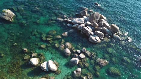 Pull-Up-Drone-Aerial-View-on-Colorful-Coast-of-Lake-Tahoe,-Clear-Blue-Alpine-Water-and-Green-Evegreen-Forest,-USA