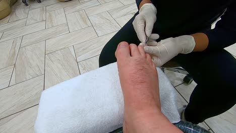 Ein-Professioneller-Fußpfleger-Schneidet-Die-Nagelhaut-Am-Rechten-Mittleren-Zeh-Eines-Mannes-Mit-Einer-Nagelhautzange