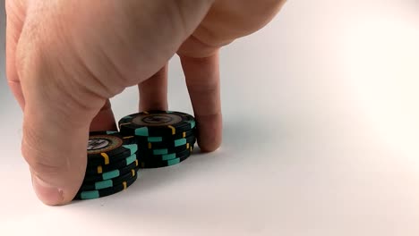 Male-hand-shuffling-black-poker-chips-on-a-white-table,-STILL,-ISOLATED,-SLOMO