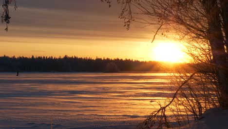 Sunlight-lighting-up-frozen-lake,-snow-landscape-during-winter-solstice