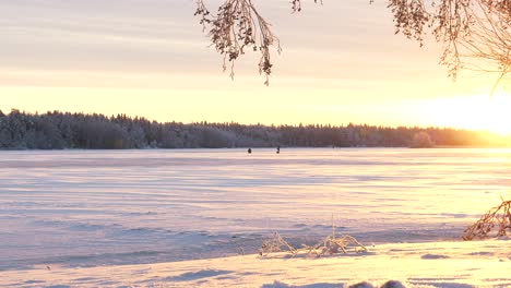 Schöner-Sonnenuntergang,-Der-Die-Winterseelandschaft-Und-Geduldige-Eisfischer-Beleuchtet