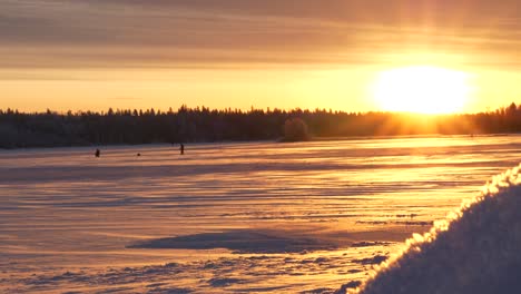 Golden-sunrise-shining-on-snowy-winter-landscape-in-the-North,-early-morning-fishermen,-dolly-slide