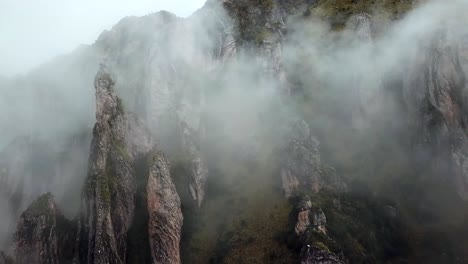 Aéreo,-En-Ascenso,-Disparo-De-Drones-Hacia-Picos-Rocosos-Y-Niebla,-En-Las-Montañas-De-Los-Andes,-En-Un-Día-Nublado,-Cerca-De-Cusco,-En-Perú,-Sudamérica