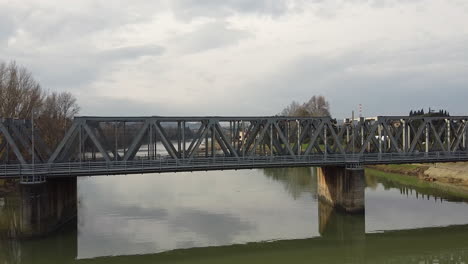 Drone-Vuela-Rápidamente-Sobre-El-Agua-Lejos-De-Un-Puente-Sobre-El-Río-Arno