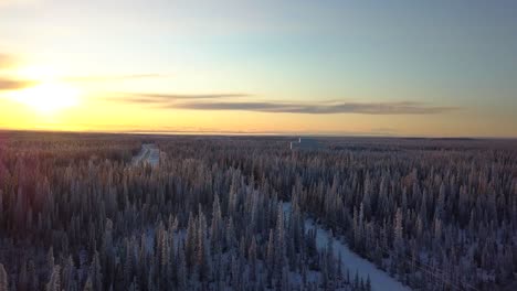 Aerial,-drone-shot,-over-snowy-forest,-towards-the-HAARP-Alaska-facility,-at-sunset,-on-a-cold-and-sunny,-winter-day,-in-Gakona,-USA
