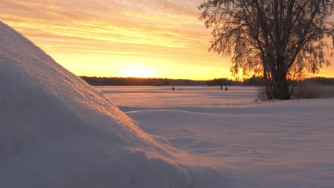 Kamerafahrt-Von-Menschen-Beim-Eisfischen-Auf-Dem-Schneebedeckten-Meer-Bei-Sonnenuntergang-An-Einem-Sonnigen-Winterabend-In-Österbotten,-Finnland