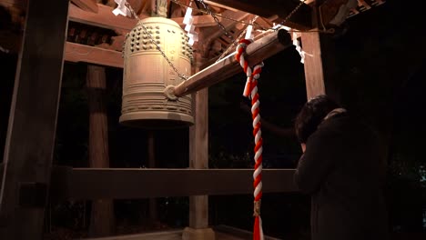 Niña-Golpeando-La-Campana-En-El-Santuario,-Tradición-De-Año-Nuevo-Japón