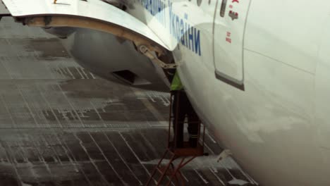 A-member-of-the-airport-staff-stands-on-a-ladder-near-a-luggage-cabin