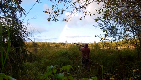 Beautiful-rainbow-and-Bird-hunter-aiming-shotgun-in-amazing-natural-scenery