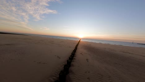Fast-shot-following-a-row-of-wooden-logs-towards-the-sunset-on-a-quiet-beach