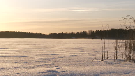 Silhouette-of-two-ice-skaters-on-a-frozen-winter-lake,-slider-shot