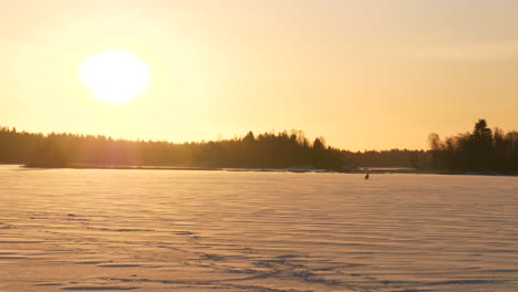 Einsamer-Mann,-Der-Auf-Einem-Zugefrorenen-See-In-Der-Winterlandschaft-Fischt-Und-Das-Einfache-Leben-Im-Arktischen-Klima-Veranschaulicht