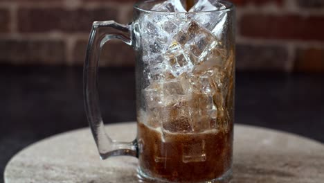 Iced-drink-poured-into-glass-cup-with-ice-cubes