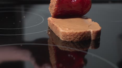 A-peanut-butter-and-strawberry-jam-sandwich-being-squished-together-on-a-black-surface