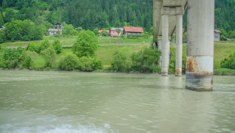 Vista-Desde-Un-Barco-Que-Navega-Por-El-Río-Drava-Y-Pasa-Por-Debajo-De-Un-Puente-En-Eslovenia