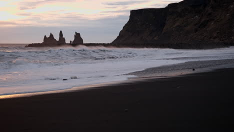 An-iconic-Icelandic-black-sand-beach-in-Vik-Iceland-at-sunset-with-waves-crashing-over-black-sand