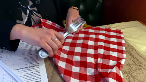 A-Caucasian-lady-unrolling-her-napkin-with-cutlery,-at-a-restaurant,-before-her-meal