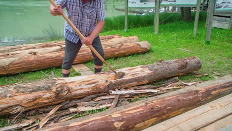 Slow-motion-shot-of-a-traditional-raftman-wood-chiselling-beside-Drava-River-in-Slovenia