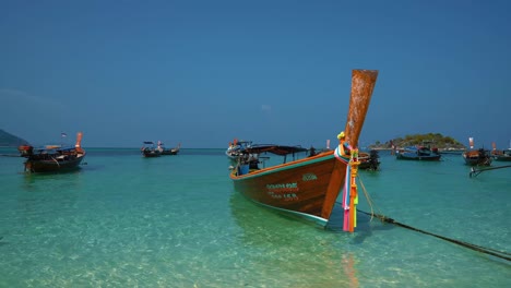 Famous,-traditional-and-iconic-longtail-boats-with-flowers-on-an-empty-sandy-beach-on-the-remote-island-Koh-Lipe-in-Thailand,-close-to-the-Malaysian-border