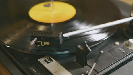 Slow-camera-move-across-a-spinning-vinyl-lp-record-as-a-hand-puts-the-needle-onto-the-grooves-of-the-record