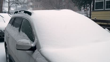 Pan-over-a-snow-covered-car-in-a-snowstorm