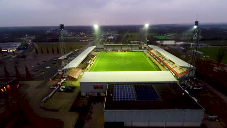 Aerial-jib-down-of-lit-up-soccer-field-in-Emmen,-the-Netherlands