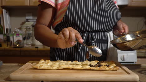 Female-cook-pours-hot-fried-mushroom-slices-on-flatbread,-slow-motion