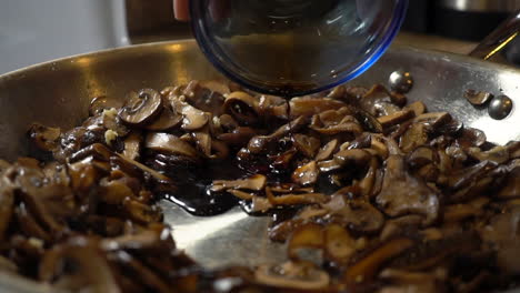 Master-chef-pours-soy-sauce-to-fried-mushroom-slices-and-stirs,-slowmo