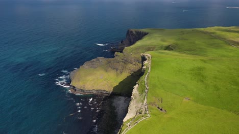 Tourists-walking-along-Cliffs-of-Moher-walking-trail,-Ireland,-aerial-flyover