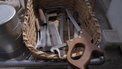 A-butcher-knife,-cutlery-and-a-saw-in-a-basket