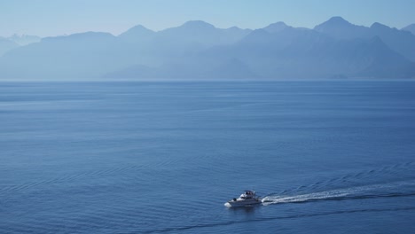 Full-shot,-boat-sailing-the-Mediterranean-sea,-toros-mountain-range-in-the-background