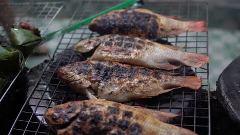 Whole-fishes-is-being-cooked-on-metal-grid-grill-at-the-street-near-a-restaurant-in-Pekin