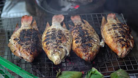 Whole-Sea-fish-is-being-cooked-on-metal-grid-grill-at-the-street-near-restaurant-in-Thailand