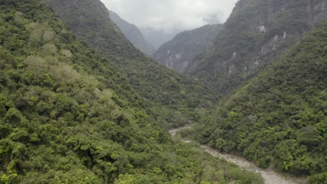 Aerial-view-following-winding-river-along-lush-green-Taroko-Valley-jungle-woodland-wilderness