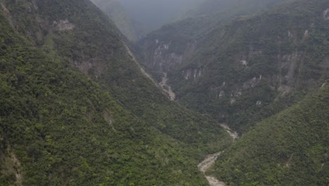 Aerial-view-rising-above-winding-river-along-tropical-green-Taroko-Valley-dense-jungle-woodland-wilderness