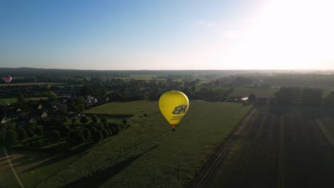 Yellow-Hot-Air-Balloon-Flying-Over-The-Fields-Near-The-Glamping-Parc-Buitengewoon-In-Netherlands
