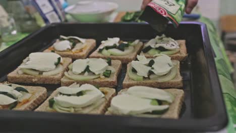 Adding-herbs-to-toasts-on-a-tray-ready-to-be-baked