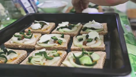 Making-toasts-on-a-baking-tray-with-green-spicy-jalapeno-pepper,-white-onion-and-mozzarella-cheese