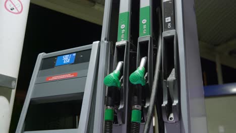 Person-picks-up-fuel-handle-to-begin-refueling-car's-tank-on-a-petrol-station