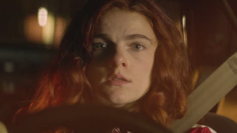 A-red-haired-woman-stares-into-the-camera-while-sitting-in-her-car