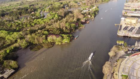 Aerial-tracking-shot-of-boat-cruising-on-stream-near-forest-landscape-in-Buenos-Aires