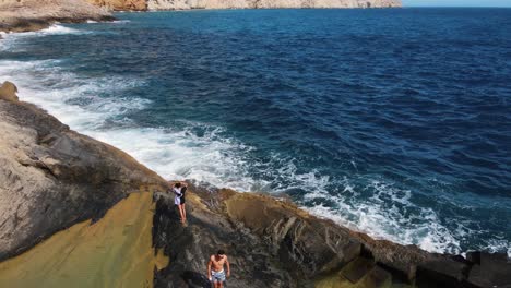 Vista-Aérea-De-Unos-Amigos-Disfrutando-De-Unas-Piscinas-Naturales-En-Una-Formación-Geológica-En-La-Costa-De-Ibiza