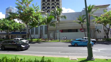 Traffic-driving-down-Kalakaua-Avenue-in-Waikiki-Honolulu-Hawaii-with-palm-trees
