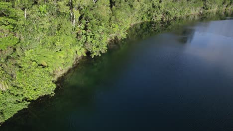 Flying-Above-Calm-Waters-Of-Lake-Eacham-In-Atherton-Tableland,-Queensland,-Australia---drone-shot