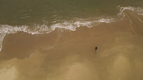 Aerial-top-down-shot-of-surfer-entering-Atlantic-Ocean-at-La-Pedrera-Beach-in-Uruguay-during-sunny-day