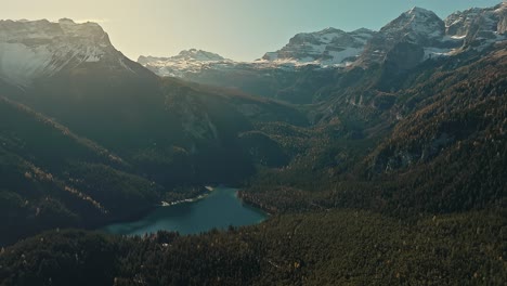 Wide-drone-pan-view-on-dolomites,-rocky-mountains-in-the-Italian-Alps,-with-small-lake-and-pine-forest-in-winter-season